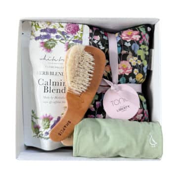 Gift box for new mums and babies with onesie, tea, and baby brush